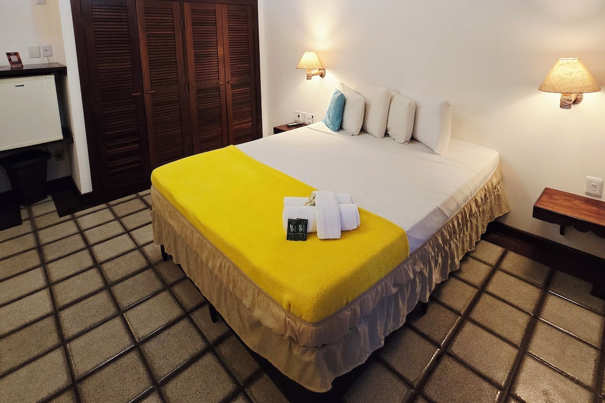 A hotel room with a bed, a desk, a wardrobe, and a lamp.