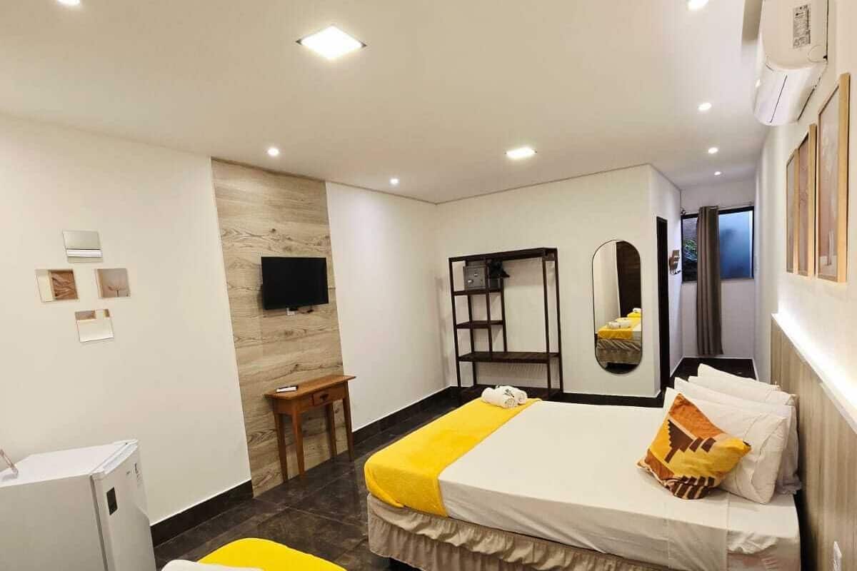 A hotel room with two beds, a small desk, a mirror, and a TV.