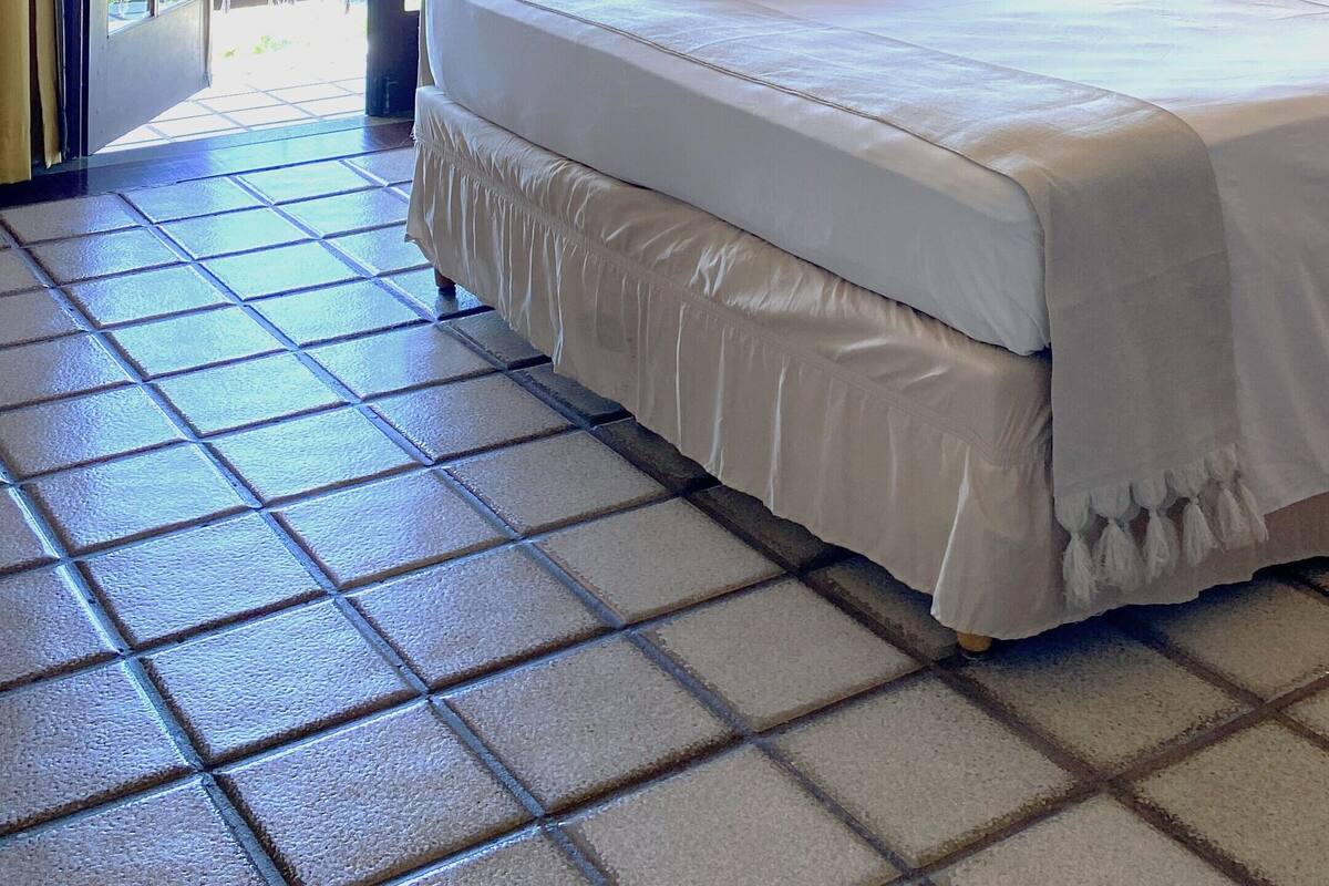 A hotel room with a bed, curtains, a window, and a view of the outside.