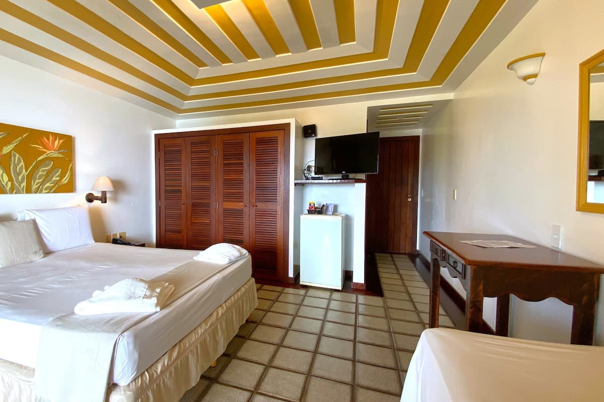 A hotel room with a bed, a desk, a television, and a kitchenette.