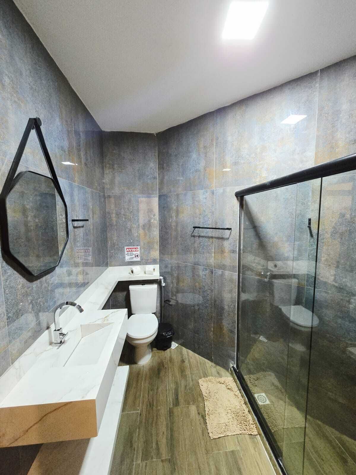 A modern bathroom with a glass shower enclosure, a white sink, and a toilet.