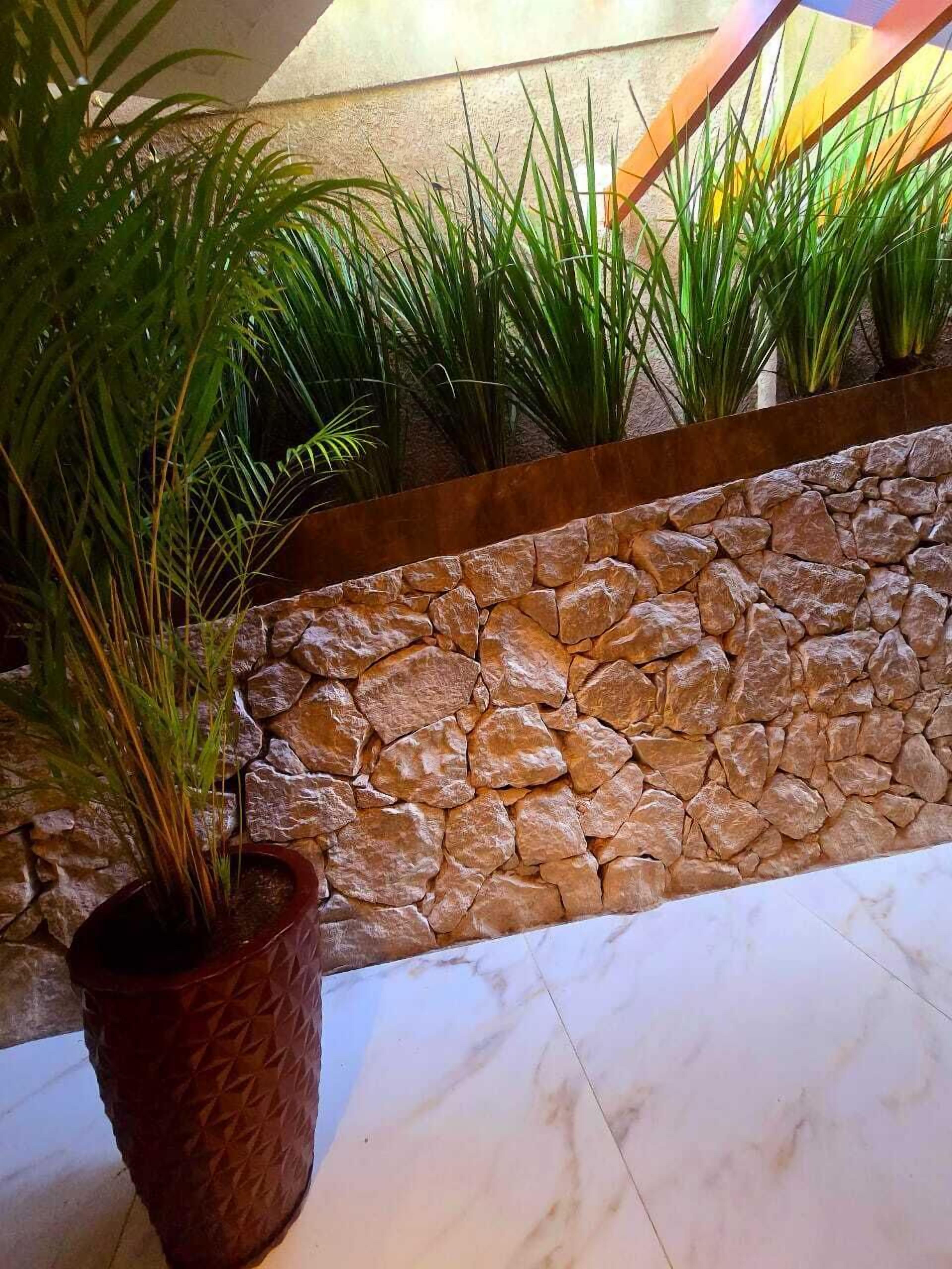 A stone wall with potted plants, a tiled floor, and a textured wall.