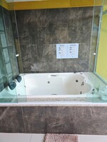 Una bañera con paredes de vidrio, una pared de mármol y un cartel con instrucciones de uso.