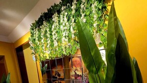 Una habitación con piso de baldosas, una planta en maceta y una pared decorada con un arreglo floral.
