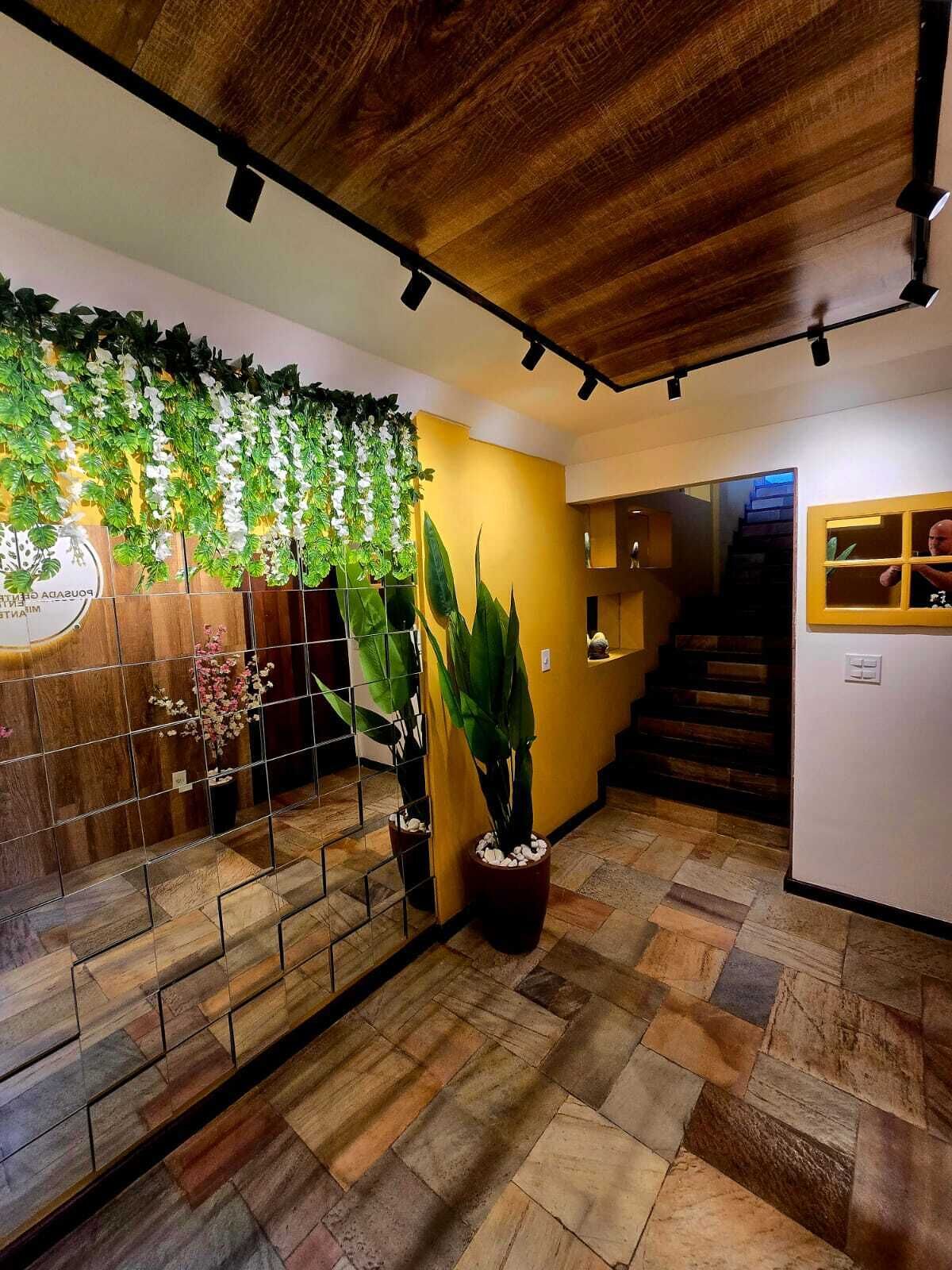 A reception area with a wooden ceiling, a staircase, and potted plants.