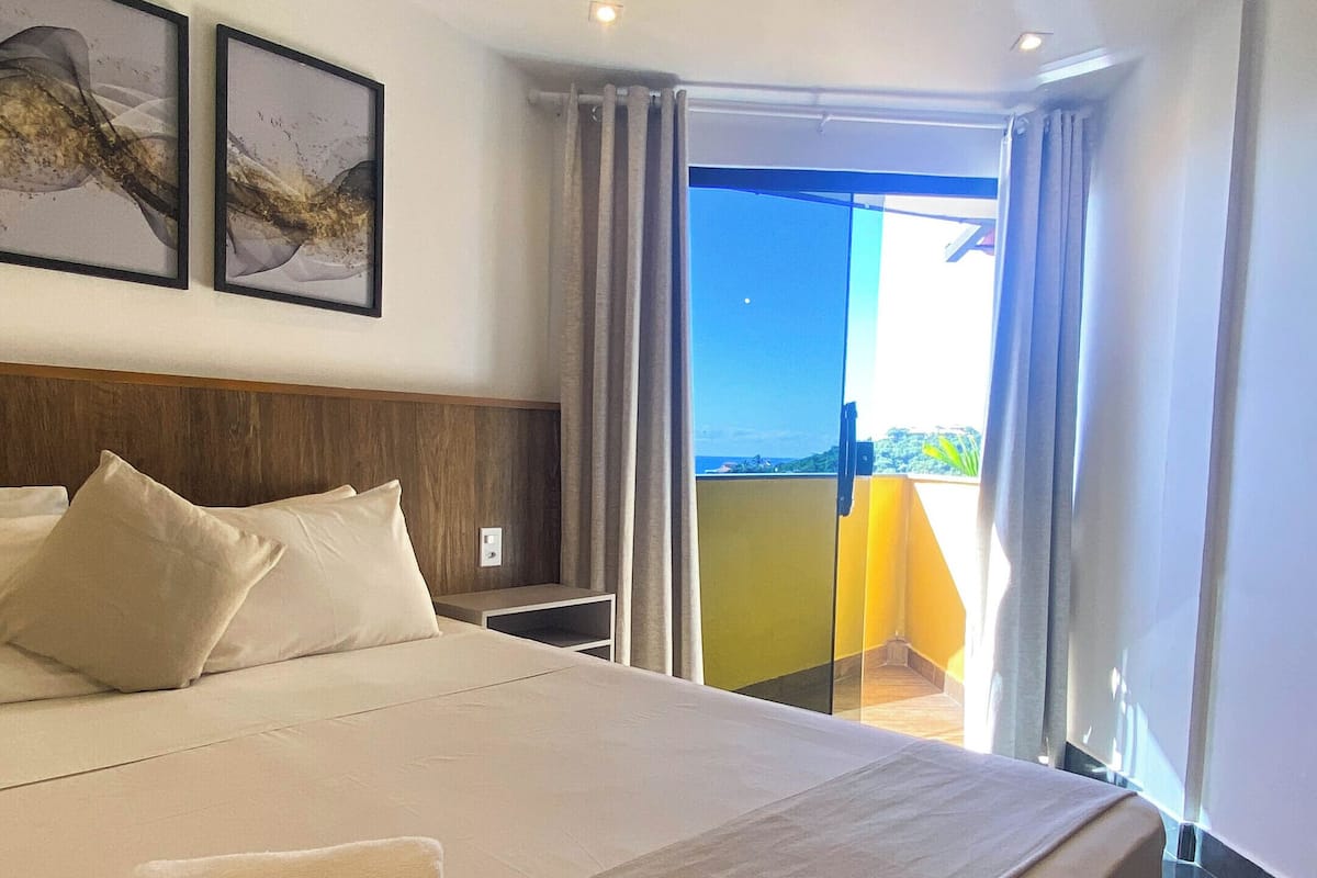 A hotel room with a large bed, a view of the outdoors, and a balcony.