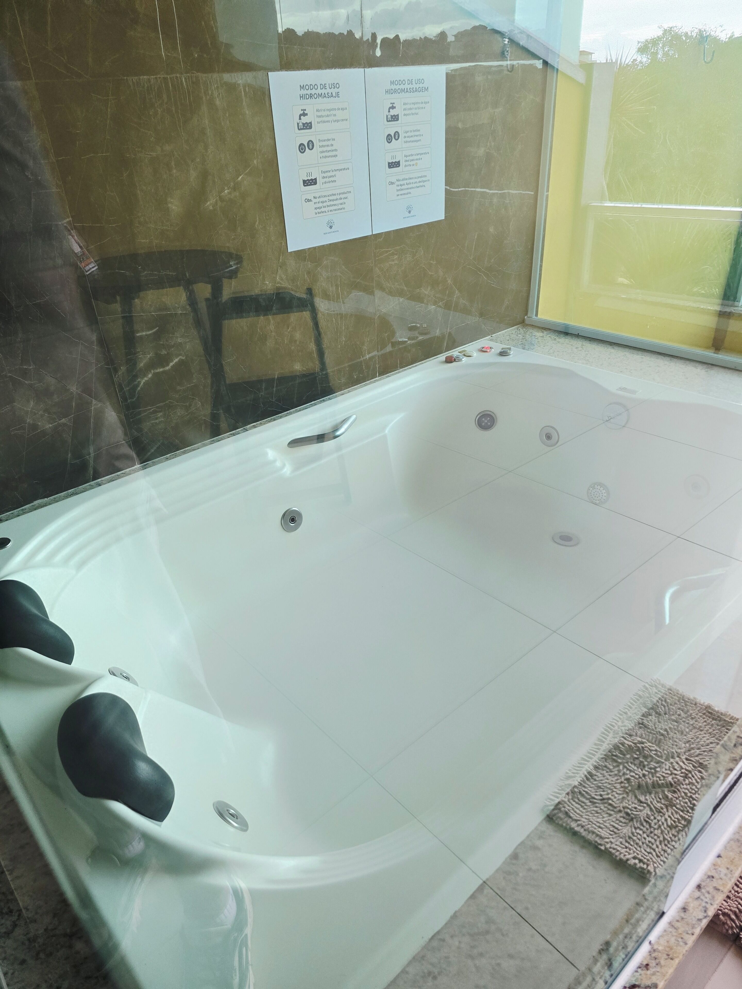 A white hot tub with control knobs, a small control panel, and a glass partition.