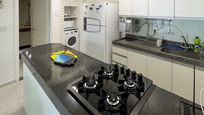 Een moderne keuken met een centraal eiland, roestvrijstalen apparatuur en een glazen afzuigkap boven het fornuis.