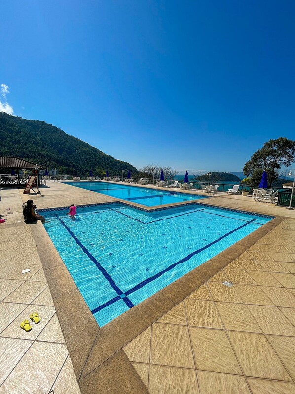 Una piscina al aire libre, sombrillas, sillones reclinables de piscina