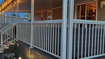 Eine überdachte Veranda mit Lichterketten, Holzgeländern und einem Kiesweg.