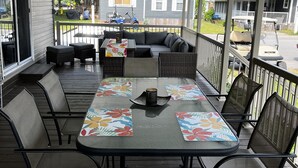 Une terrasse extérieure couverte, avec une table dressée pour quatre personnes, entourée de chaises.