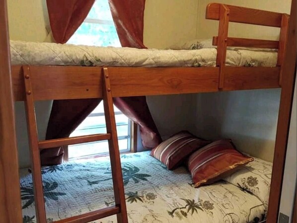 A bunk bed with a ladder, a window with curtains, and a floral-patterned bedspread. - Beautiful privately-owned  cottage in sherkston shore resort. (Port Colborne)
