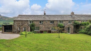 A stone house with a grassy yard and a mountain in the background. - Flaska House (Penrith)