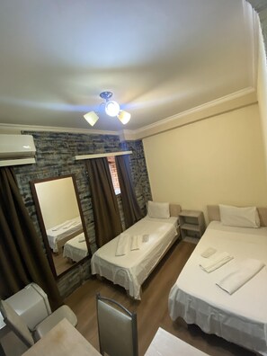 A hotel room with two single beds, a desk with a chair, a small table, an air conditioning unit, a mirror, and a ceiling fan. - Unique and Cozy Apart Hotel on the corner of London Park in Tbilisi (T'bilisi)