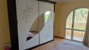 A bedroom with a bed, a sliding door with decorative patterns, and a view of a balcony.