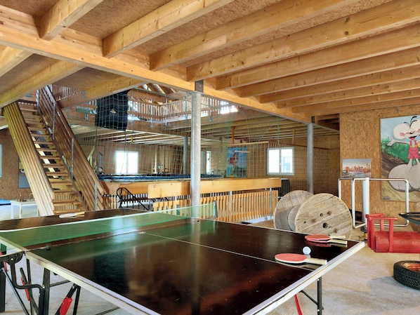 A ping pong table, wooden beams, a staircase, and a mural.