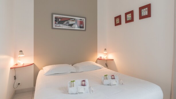 A hotel room with a bed, two bedside tables, a framed picture on the wall, and a small window. - La Birochère - 400 m plage - Parking (Pornic)