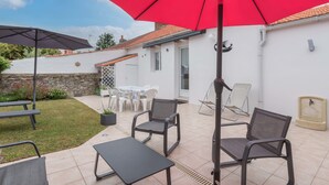 An outdoor patio area with a red umbrella, two black tables, and four chairs. - La Birochère - 400 m plage - Parking (Pornic)
