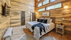 Un dormitorio acogedor con una cama grande, un banco, una mesita de noche y un reloj de pared.
