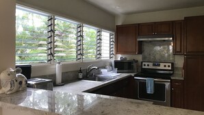 A kitchen with a large window, stainless steel appliances, and wooden cabinets.