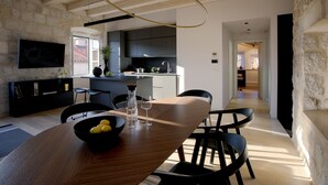 A modern kitchen with dark cabinets, a wooden dining table, and a black sofa.