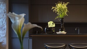 A modern kitchen with dark cabinetry, a vase with flowers, and two bar stools.
