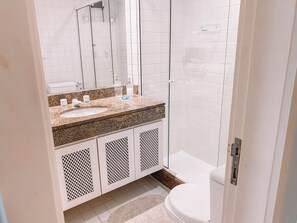 A modern bathroom with a granite countertop sink, a glass shower enclosure, and a toilet. - Apt Porto Real Resort Columbia (Angra dos Reis)