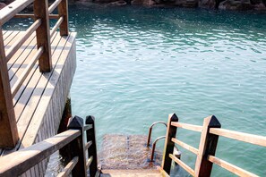 A wooden pier leading into calm water with a rocky shoreline in the background. - Apt Porto Real Resort Columbia (Angra dos Reis)