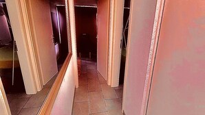 Un pasillo estrecho con suelo de baldosas y puertas que dan a otras habitaciones.