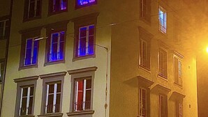 Un edificio de varios pisos con ventanas iluminadas y un escaparate visible a nivel de la calle.