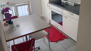 Una cocina pequeña con armarios blancos, encimera negra y alfombra roja.
