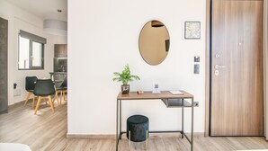 Quarto moderno com escrivaninha de madeira, espelho redondo, planta em vaso e uma porta.