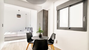 Quarto moderno com uma mesa redonda, duas cadeiras pretas, um vaso de planta e uma janela grande.