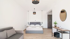 Quarto moderno com cama, sofá, escrivaninha e espelho.