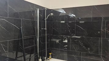 Une salle de bain moderne avec une douche en marbre noir, une baignoire blanche et un lave-linge.