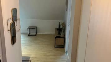 A hallway with wooden flooring, a small table, and a cabinet.