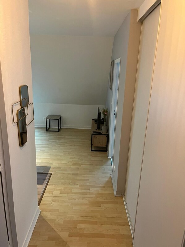 A hallway with wooden flooring, a small table, and a cabinet.