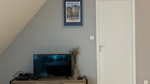 Habitación con una unidad de entretenimiento de madera, un televisor de pantalla plana, un cuadro en la pared y una puerta blanca.