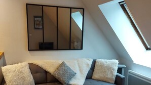 Una sala de estar moderna con un sofá modular, una mesita blanca y un espejo grande en la pared.