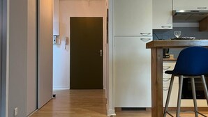 Una cocina moderna con armarios blancos, encimera de madera y una silla azul.