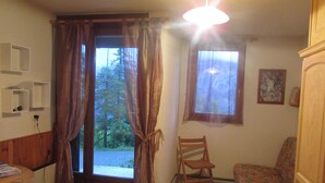 Una stanza con un armadio in legno, una sedia, un tavolino e una finestra con tende.