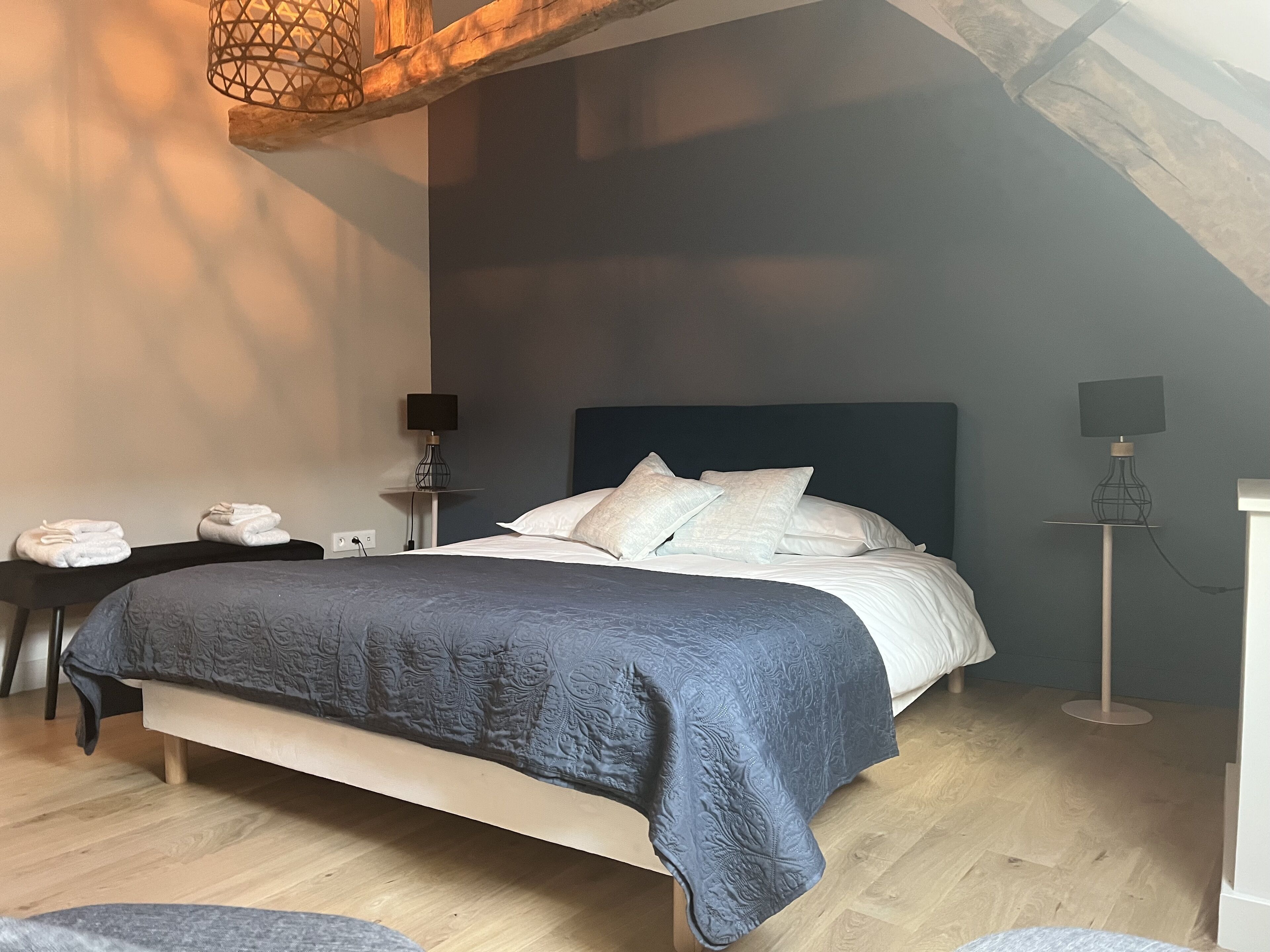 Une chambre moderne avec un grand lit, un bureau avec une chaise et une lampe sur pied.