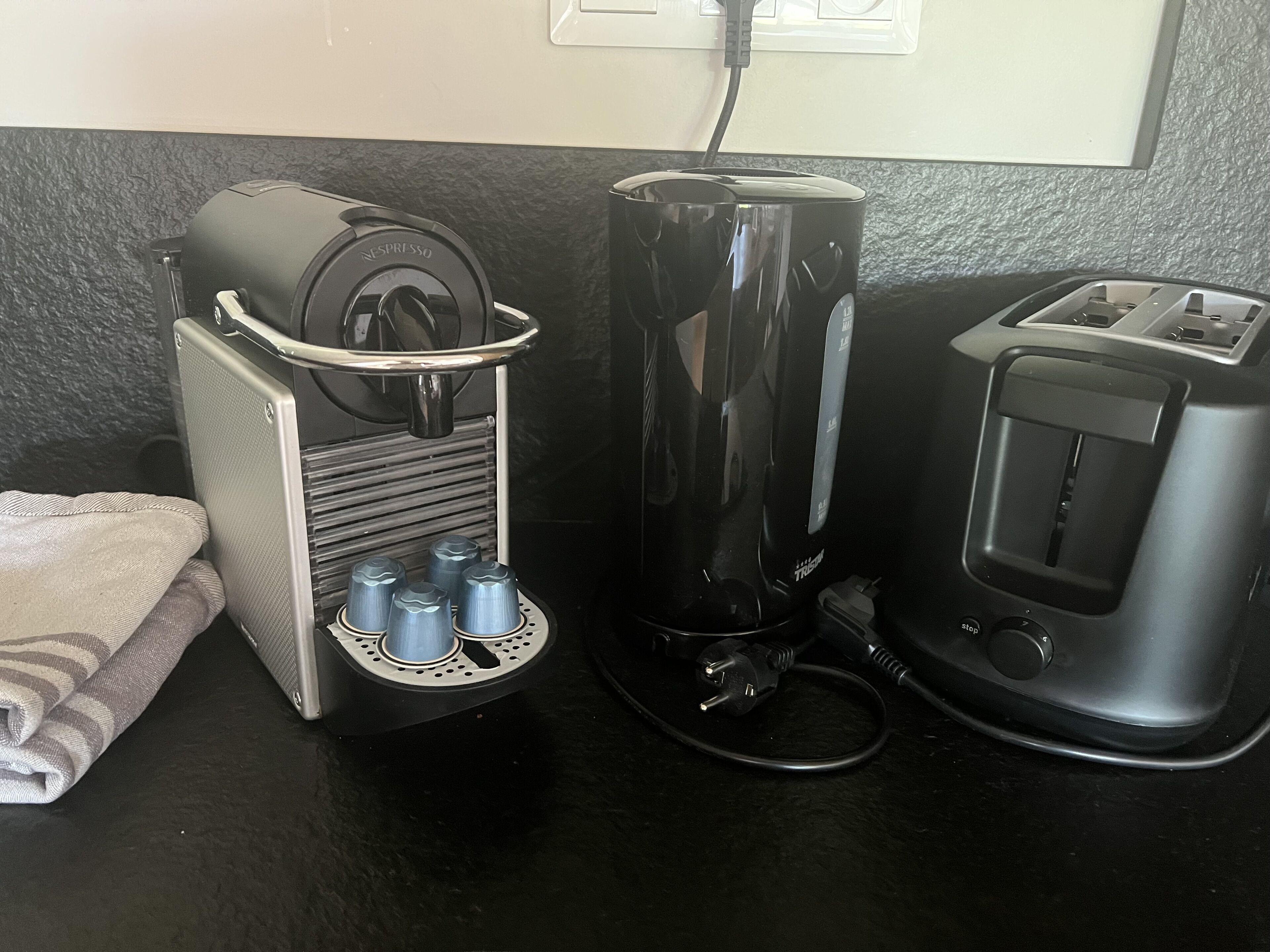 A coffee machine, a toaster, and a power strip on a countertop.
