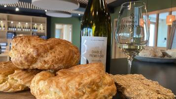 Una botella de vino Chablis Premier Cru, una copa de vino blanco y varios pasteles sobre una mesa de madera en un restaurante.