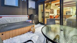 An outdoor seating area with a glass table, a wooden bench, and a glass door leading to an interior space. - skiNewpark33: Walkable w/View, Deck, Hot Tub, Garage (Park City)