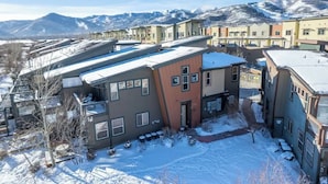 A residential area with modern houses, a small courtyard, and mountains in the background. - skiNewpark33: Walkable w/View, Deck, Hot Tub, Garage (Park City)