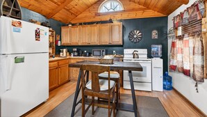 Una cocina con armarios de madera, un refrigerador, una estufa y una mesa de comedor con sillas.