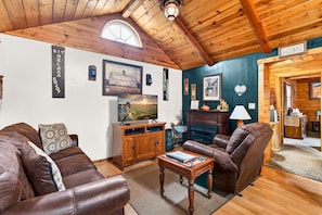 A cozy living room with a leather sofa, wooden cabinet, and fireplace.