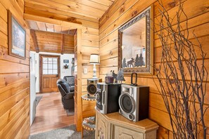 A wooden interior with a sofa, a lamp, a mirror, and a speaker setup.
