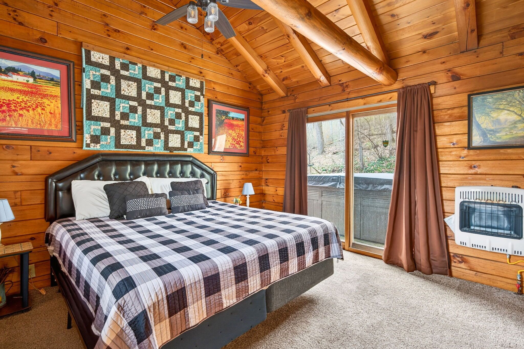 Ein Schlafzimmer in einer Blockhütte mit Bett, Decke, gerahmten Bildern und einem Heizgerät.